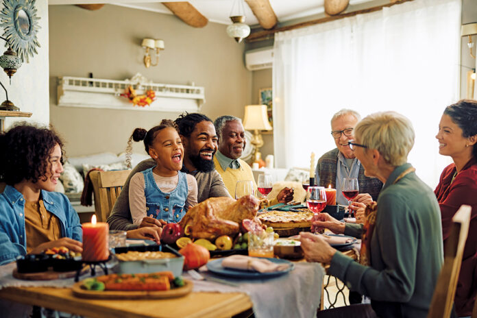 Cheerful multiracial family enjoying in conversation during Thanksgiving meal at dining table.